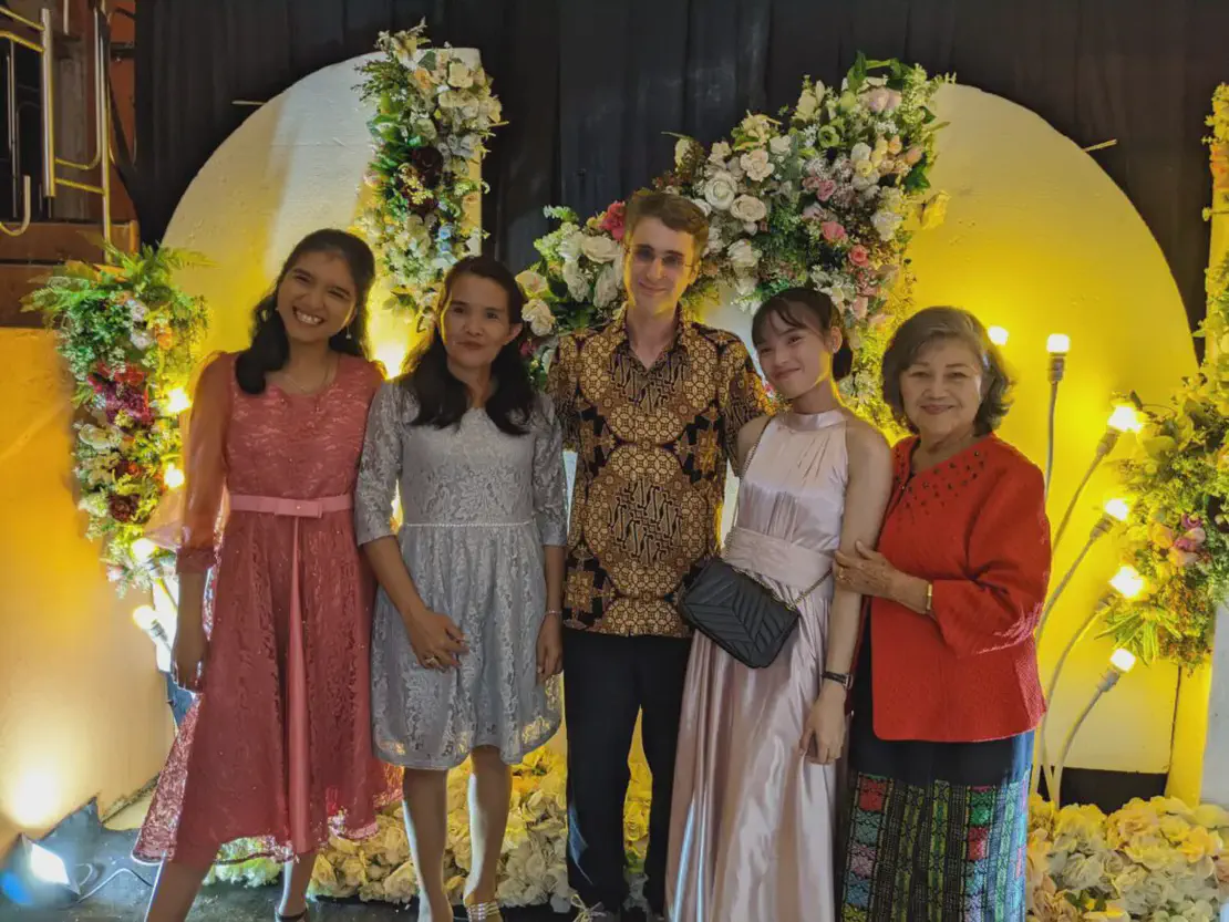 Group of five people dressed formally posing in front of a floral backdrop.