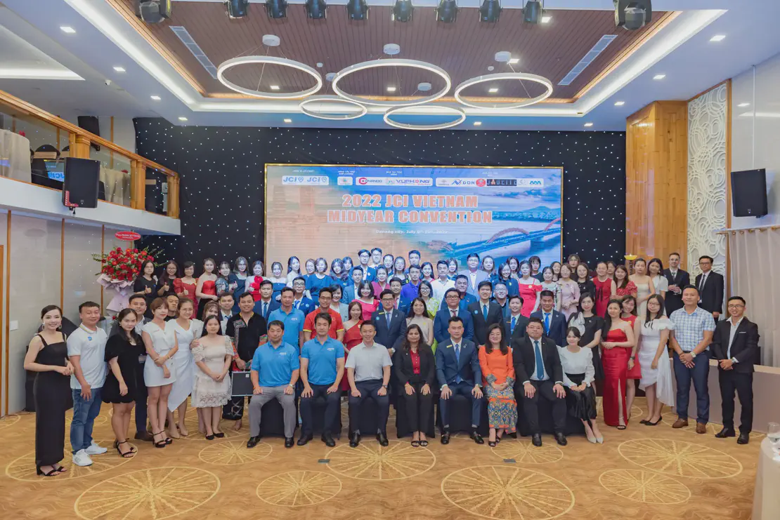 Large group photo of participants at the 2022 JCI Vietnam Midyear Convention in Da Nang City, with a stage backdrop and event banner.