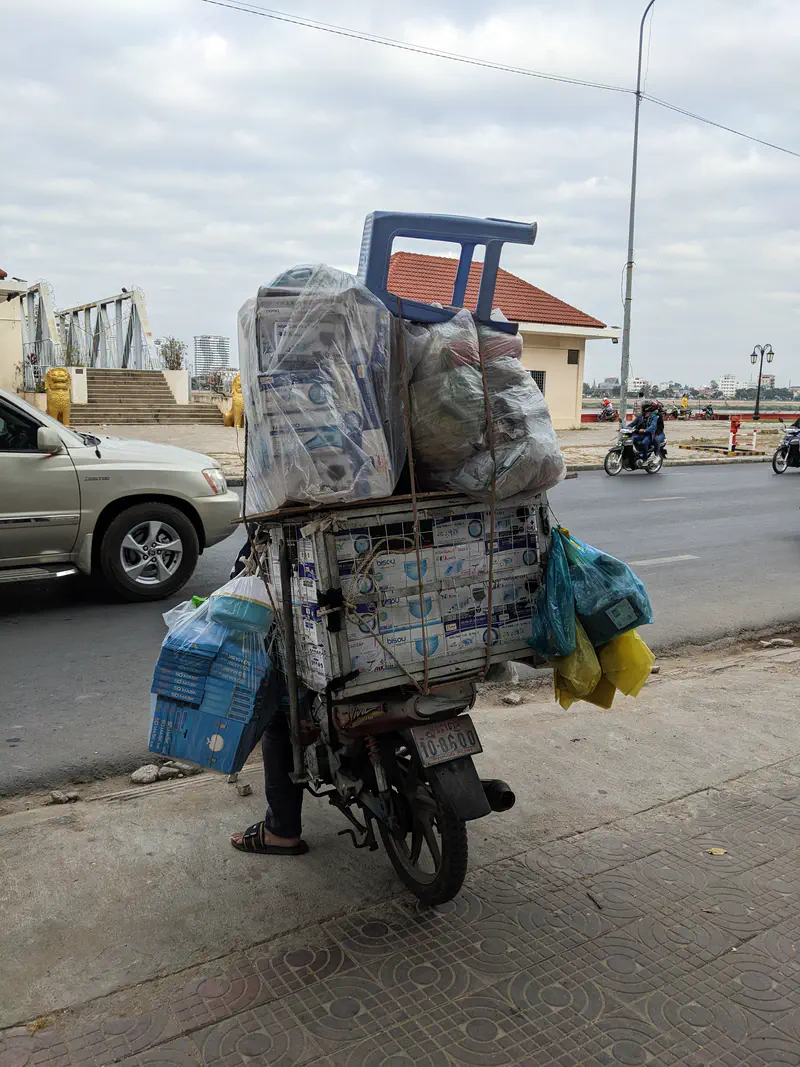 Motorbike overloaded with boxes, bags, and a plastic chair strapped on the back.