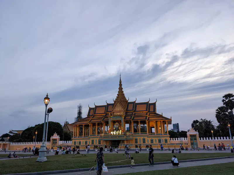 The Royal Palace in Phnom Penh at dusk with people gathered in the foreground.