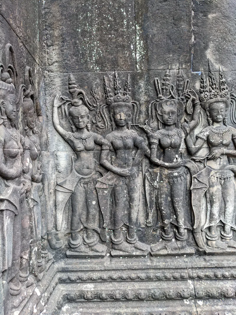 Stone carvings of apsara dancers on a temple wall at Angkor Wat.