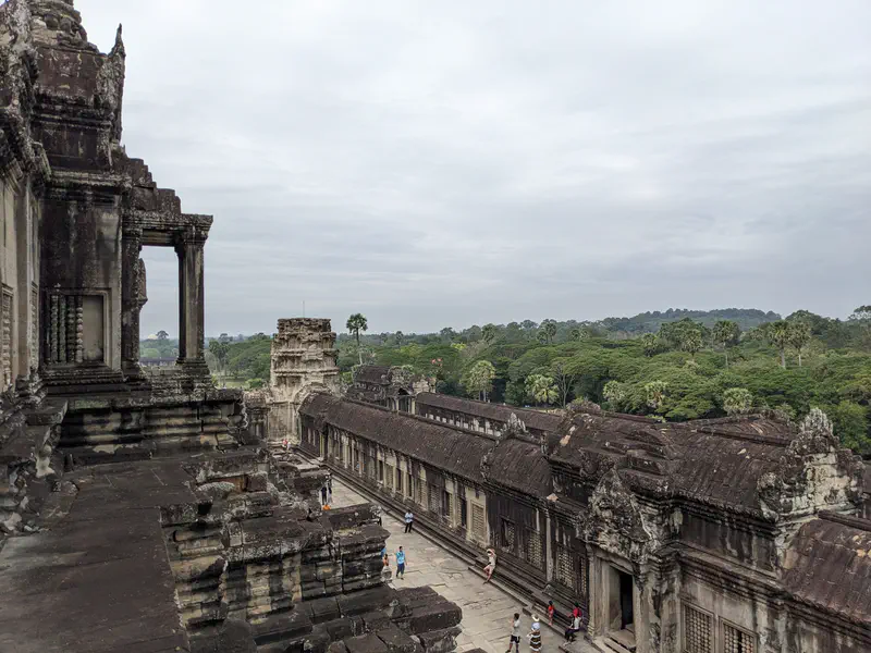 View from Angkor Wat showing stone ruins and green forest in the distance.