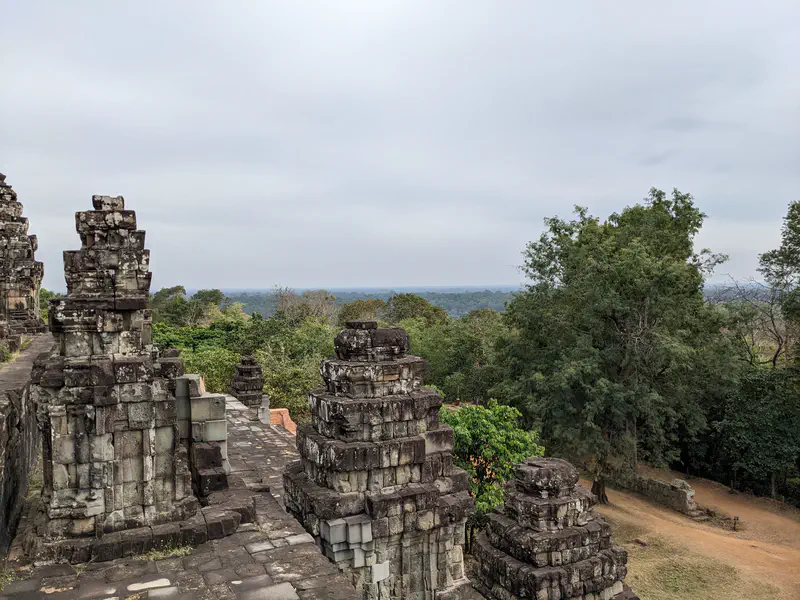 Stone pyramid temple with steep stairways and towers at Angkor complex.