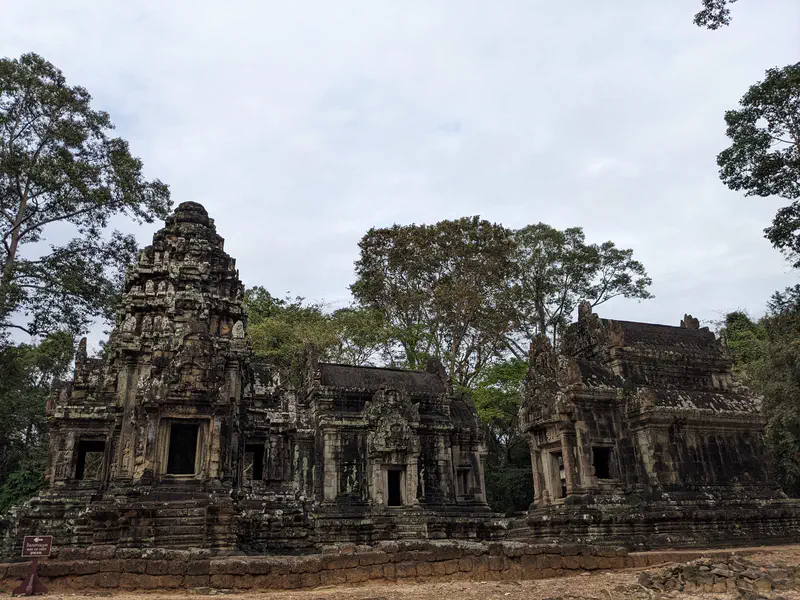 Ancient stone temple ruins with detailed carvings and towers in Angkor complex.