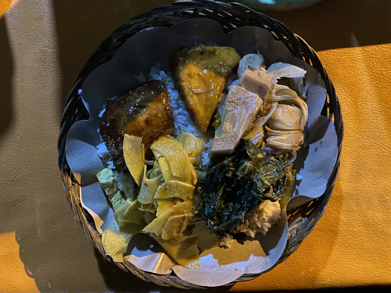 Plate of rice with fried tofu, bamboo shoots, leafy greens, and curry vegetables.
