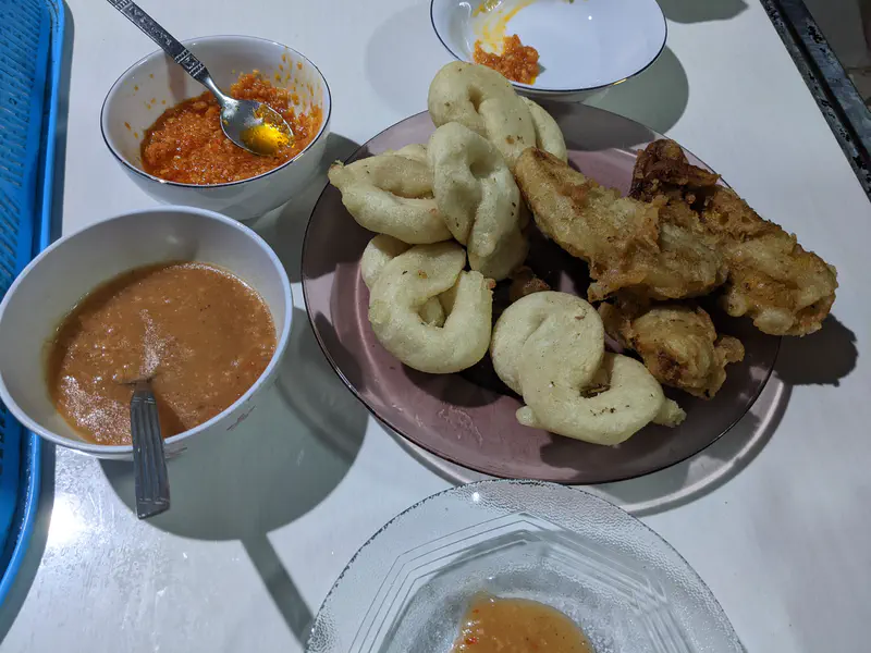 Plate of fried snacks with bowls of peanut sauce and chili sauce.