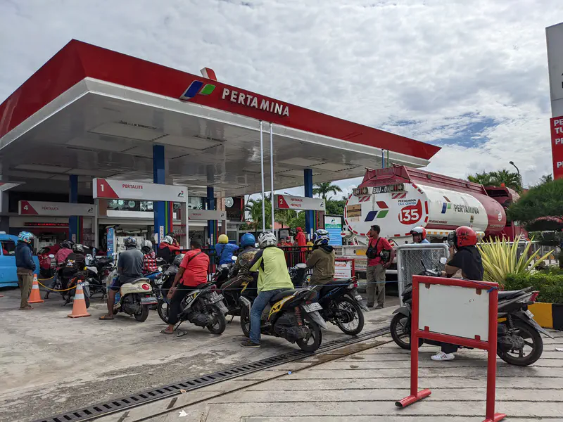 Long line of motorcycles waiting at a Pertamina gas station.