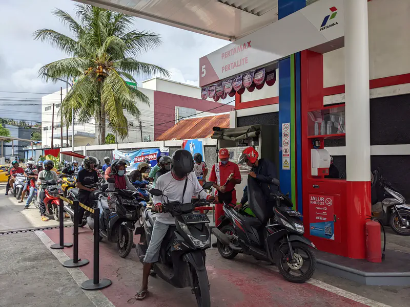 Motorcyclists lined up at a gas pump in a Pertamina station.