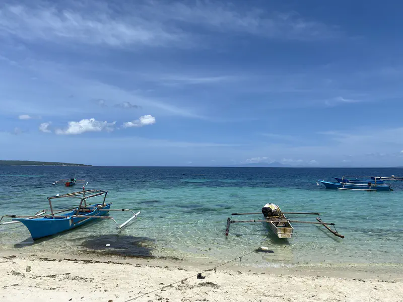 Small fishing boats anchored near the shore on a clear blue sea.