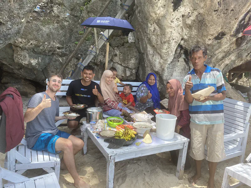Group of people enjoying a meal together at a beachside table.