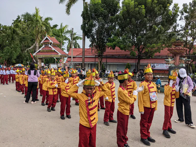 Boys in gold and red costumes with crowns marching in a parade.