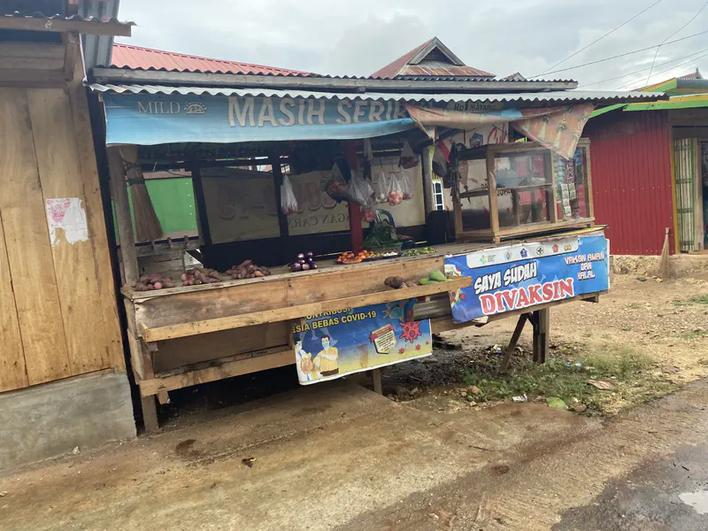 Small roadside vegetable stall with a banner promoting COVID-19 vaccination.