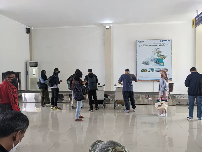 People waiting at a baggage claim area inside an airport terminal.