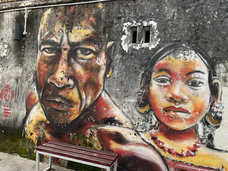 Colorful mural of a man and woman painted on a weathered wall.