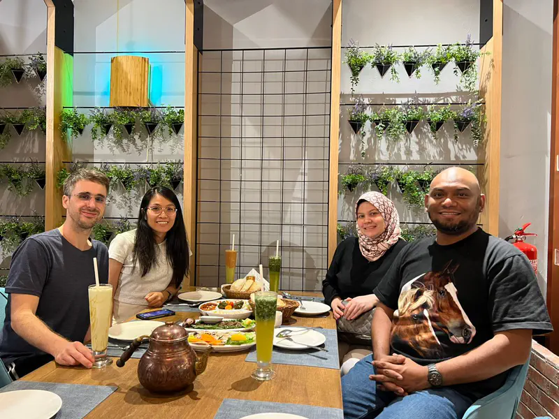 Four friends sitting at a restaurant table with Middle Eastern food and drinks.