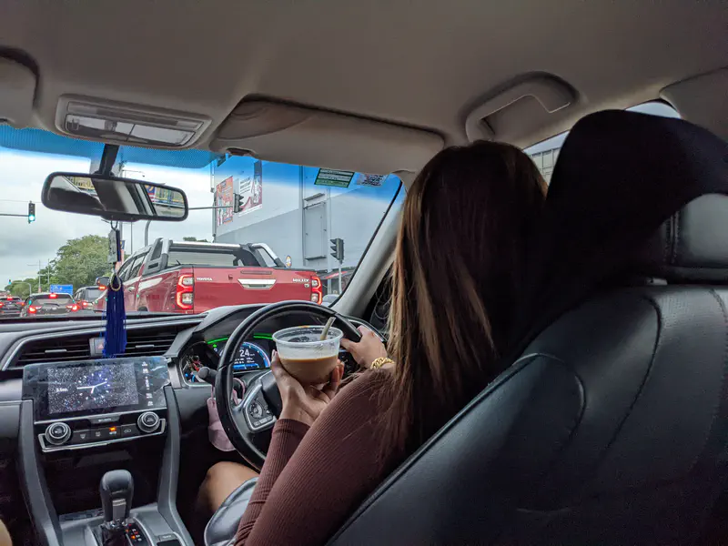 Driver holding a drink while driving a car in traffic.