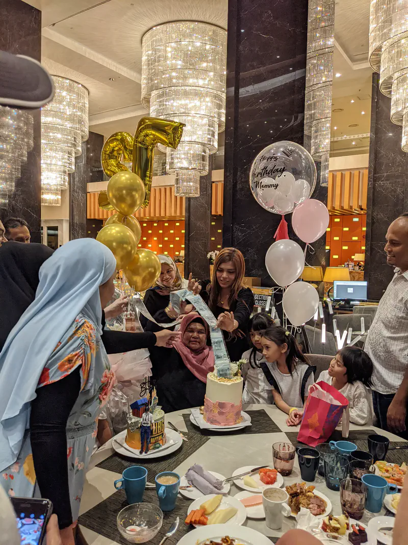 Family and children gathered around a birthday cake with money roll surprise inside.