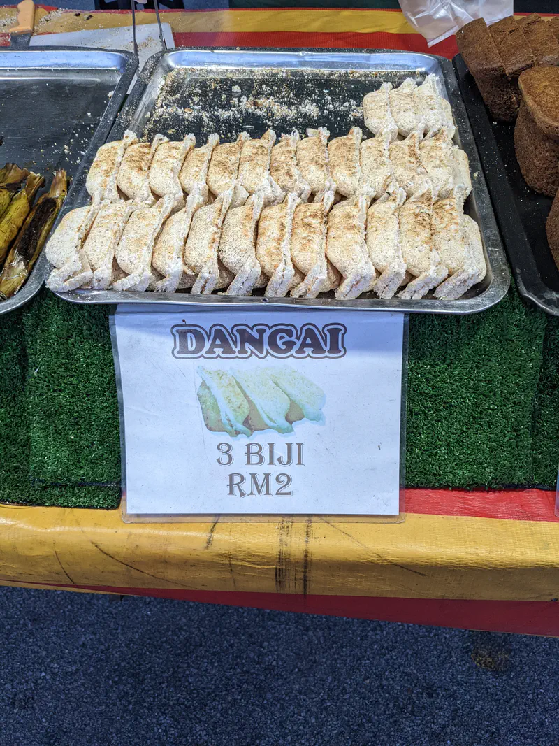 Tray of kuih dangai, a traditional Malaysian coconut cake, displayed for sale at a market stall.
