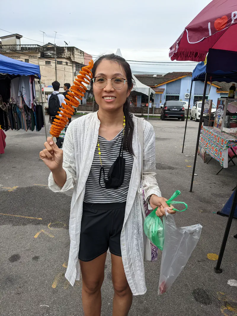 Street food stall selling putu mayong, with large trays of rice flour noodles and pre-packed portions on display.