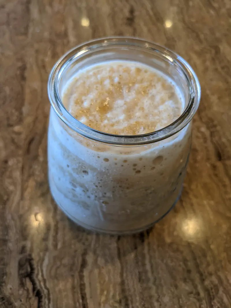 Glass jar filled with a creamy blended drink on a wooden table.