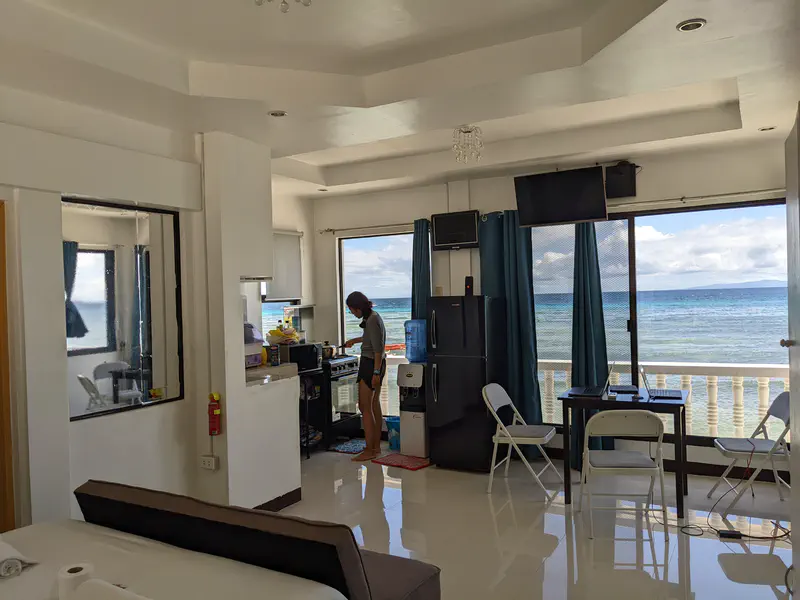 Person cooking in a bright apartment with ocean view through large windows.