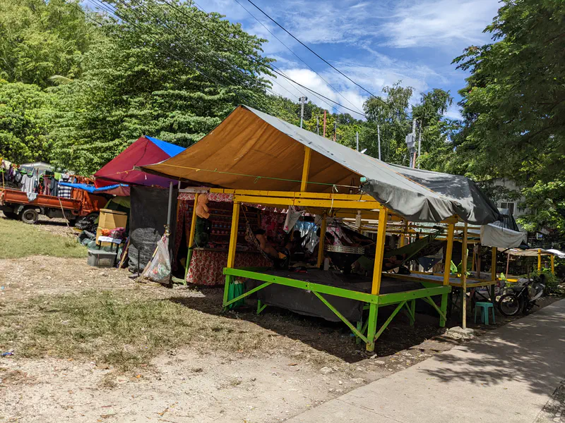 Colorful tents set up outdoors with hammocks and stalls under the shade.