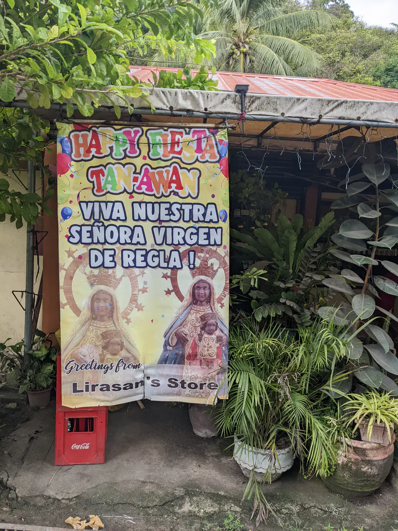 Colorful fiesta banner with images of the Virgin Mary and child outside a store.