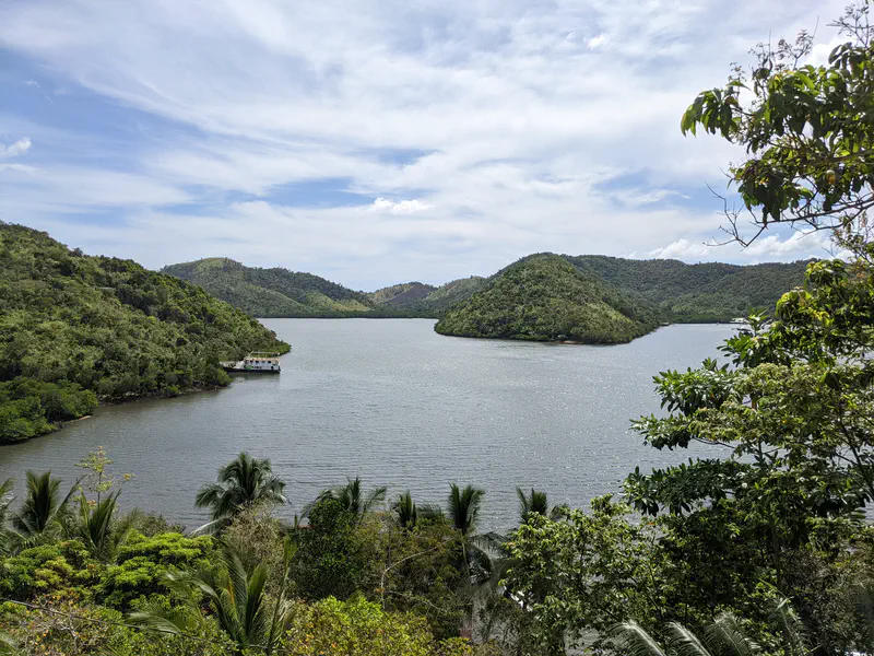 Scenic view of a bay surrounded by green hills with a boat docked near the shore.