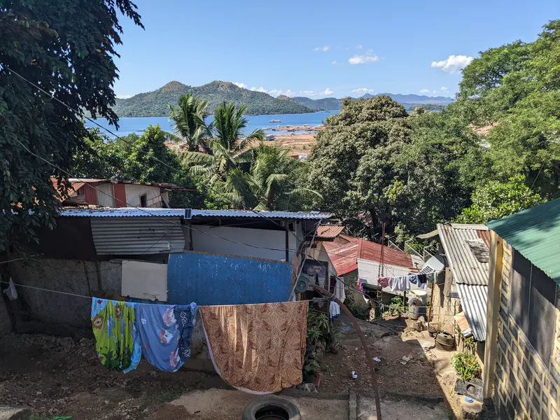 Laundry hanging on clotheslines between houses with a view of the sea and islands in the background.
