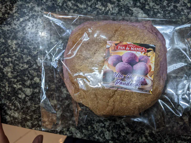 Packaged ube cheese pandesal bread from Pan de Manila on a granite countertop.
