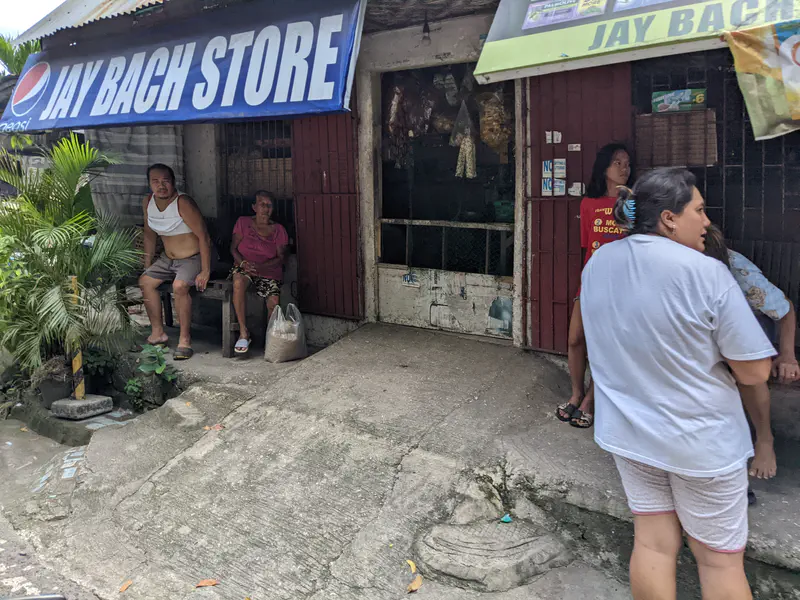 Small roadside store with people sitting and standing outside under a Jay Bach Store sign.