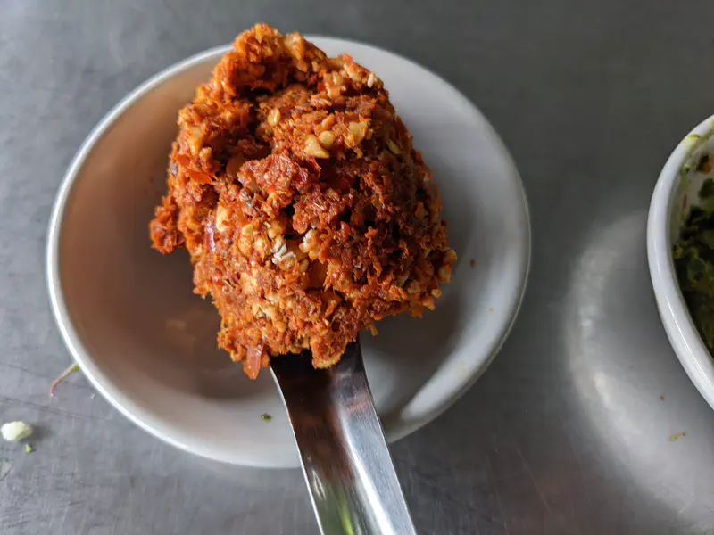 Spoonful of freshly made red curry paste served in a small white dish.