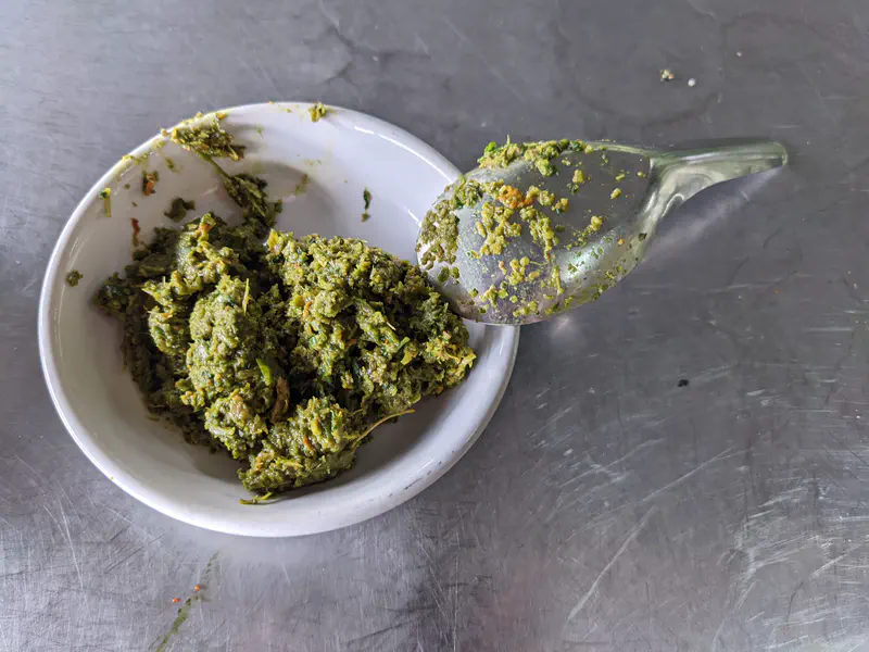 Spoonful of freshly made red curry paste served in a small white dish.