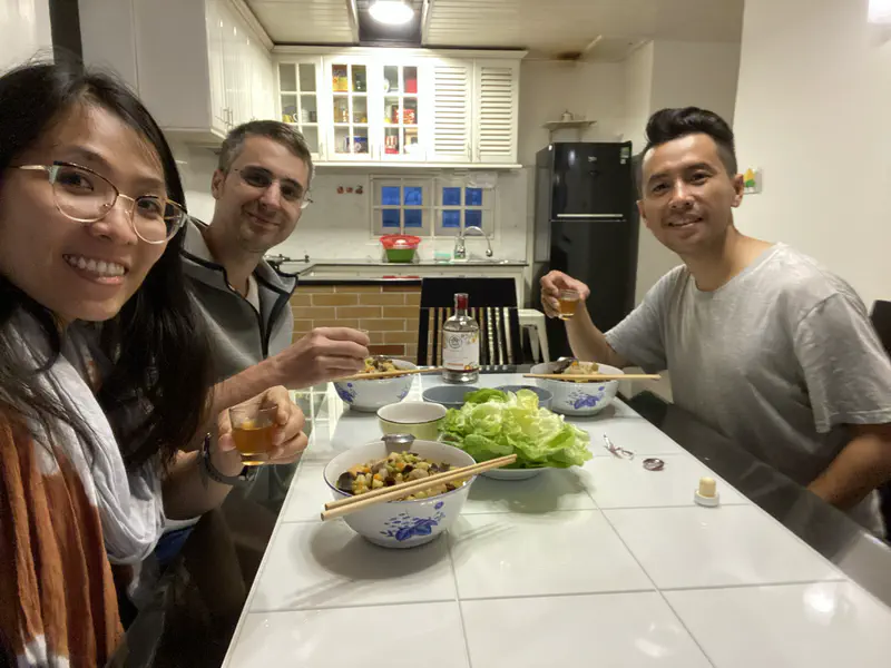 Three people smiling and enjoying a meal together at a dining table.