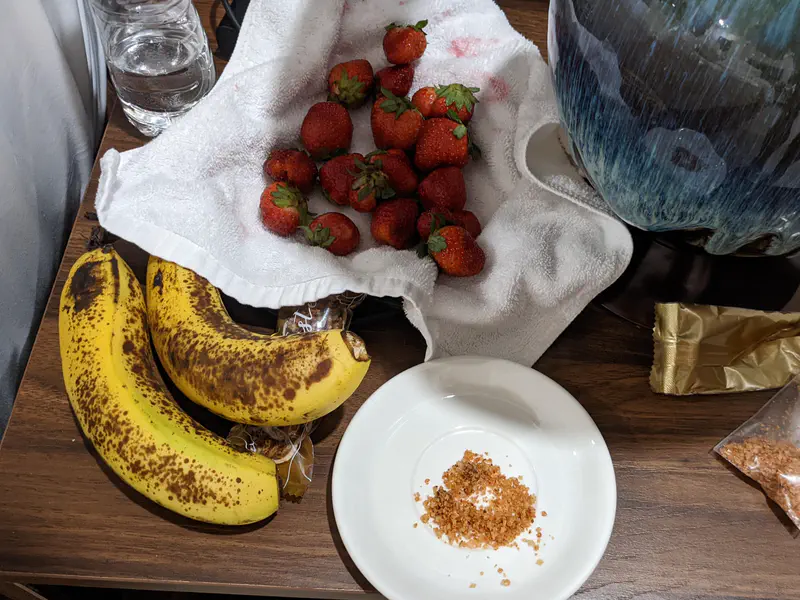 Bananas and strawberries on a wooden table with chili salt on a small plate.