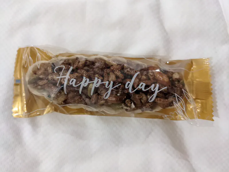 Packaged snack bar with nuts labeled 'Happy day' on a white background.