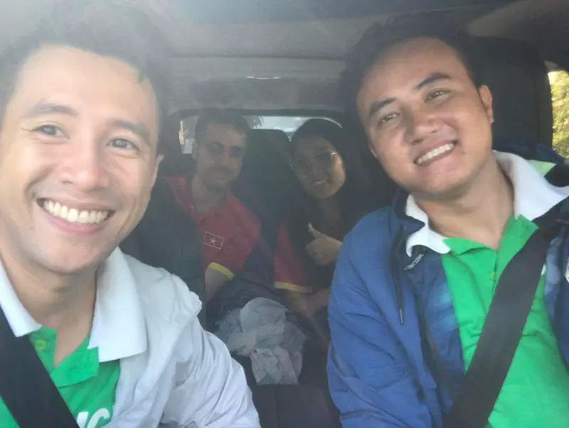 Four people smiling inside a car, two in the front and two in the back seats.