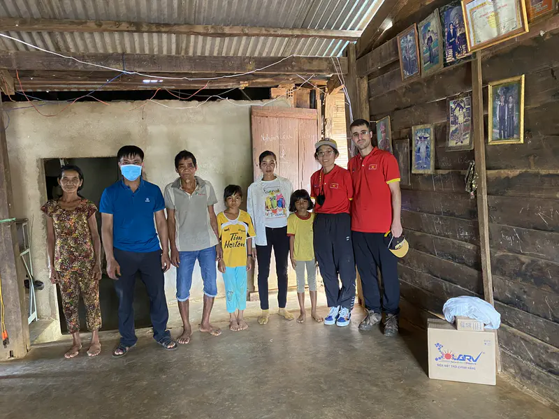 Group of people, including locals and volunteers, standing inside a wooden house.