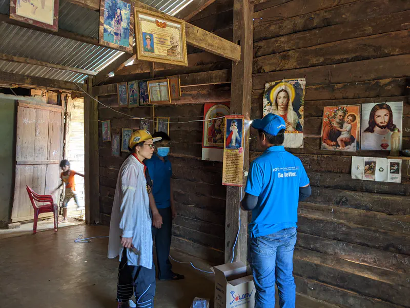 People inside a wooden house decorated with religious images, working with solar equipment.