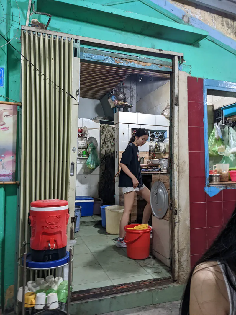 View of a small restaurant kitchen entrance with a woman preparing food inside.