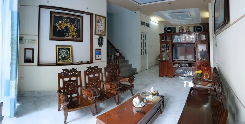 Living room with wooden furniture, framed artwork, a staircase, and a large wooden cabinet with a TV.