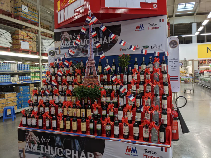 Supermarket display of French wine bottles decorated with red bows and small French flags.