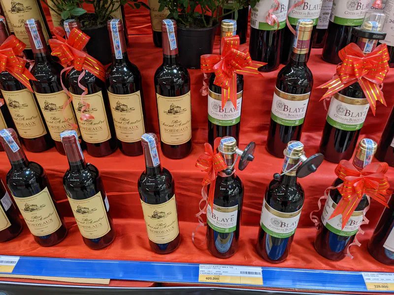 Close-up of Bordeaux wine bottles with red bows on a store shelf.