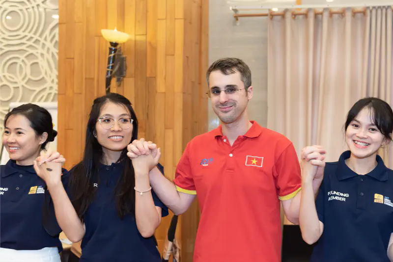 Group of people standing in a row holding hands, smiling during a JCI Vietnam event.