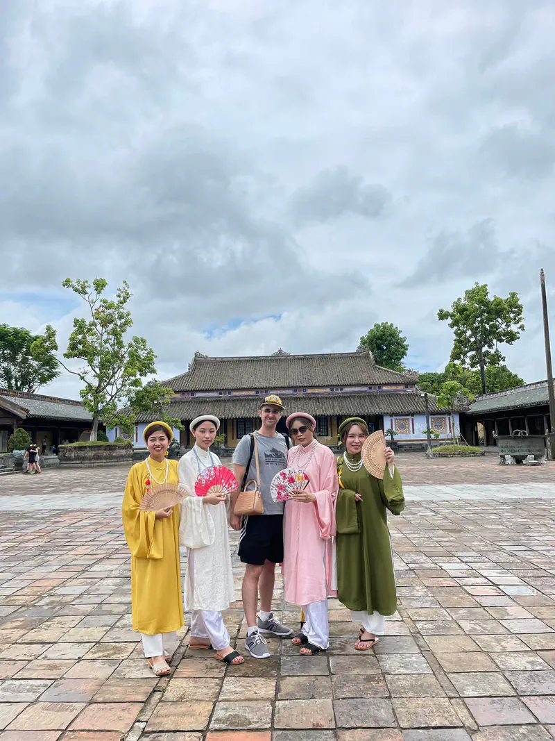 Group of people posing in traditional Vietnamese attire at the Imperial City in Hue.