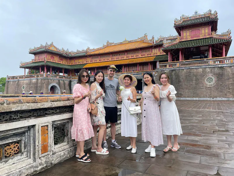 Group of six people posing in front of the historic Imperial City in Hue, Vietnam.