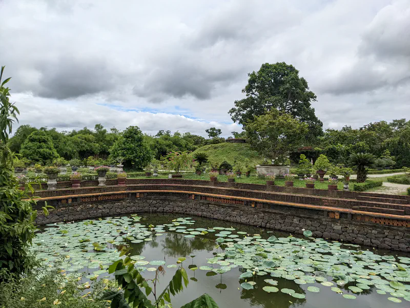Lotus pond with stone walls and surrounding greenery in a historic garden.