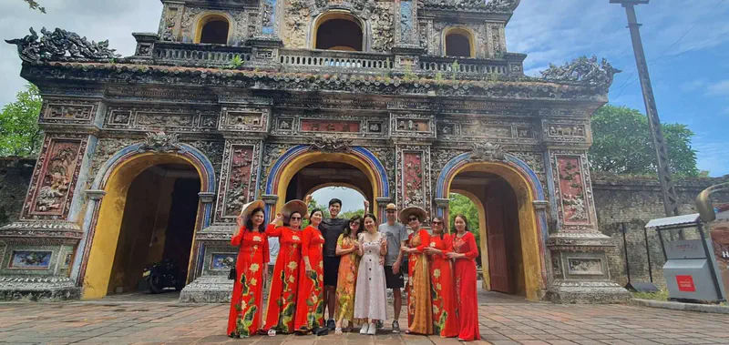 Group of people posing in front of an ornate historic gate at the Imperial City in Hue.