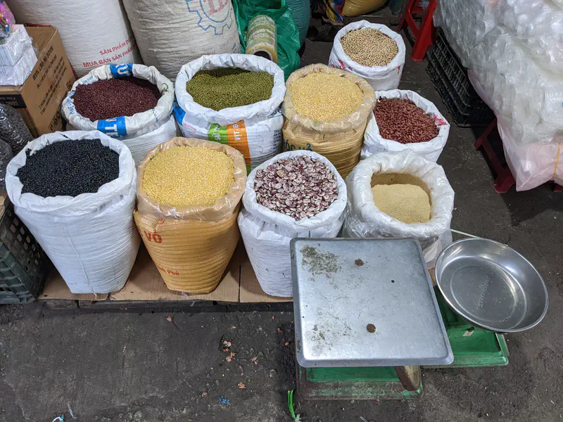 Open sacks filled with different types of beans and grains at a market.