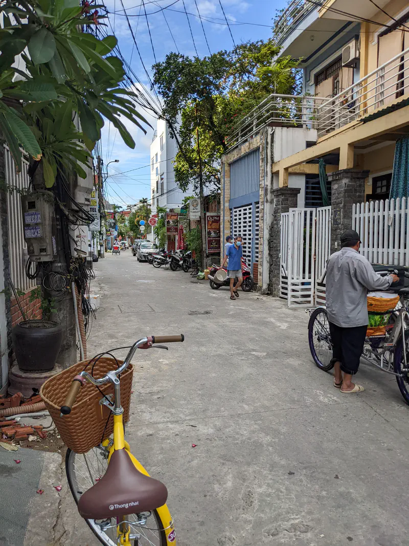 Narrow residential street with bicycles, motorbikes, and small shops in Huế.